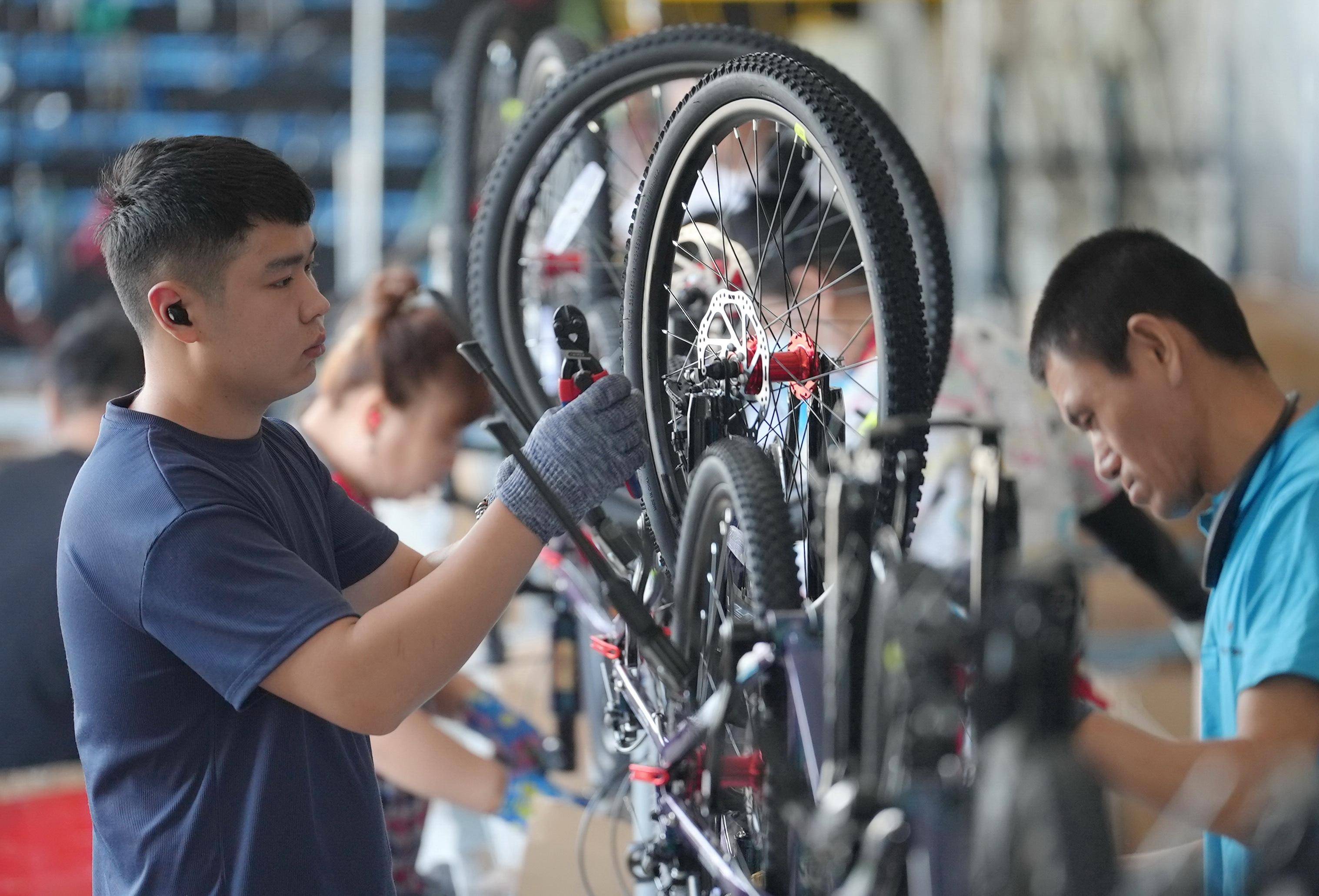 Worker installing a road bike wheel on the production line, showcasing manufacturers in the list of road bike manufacturers