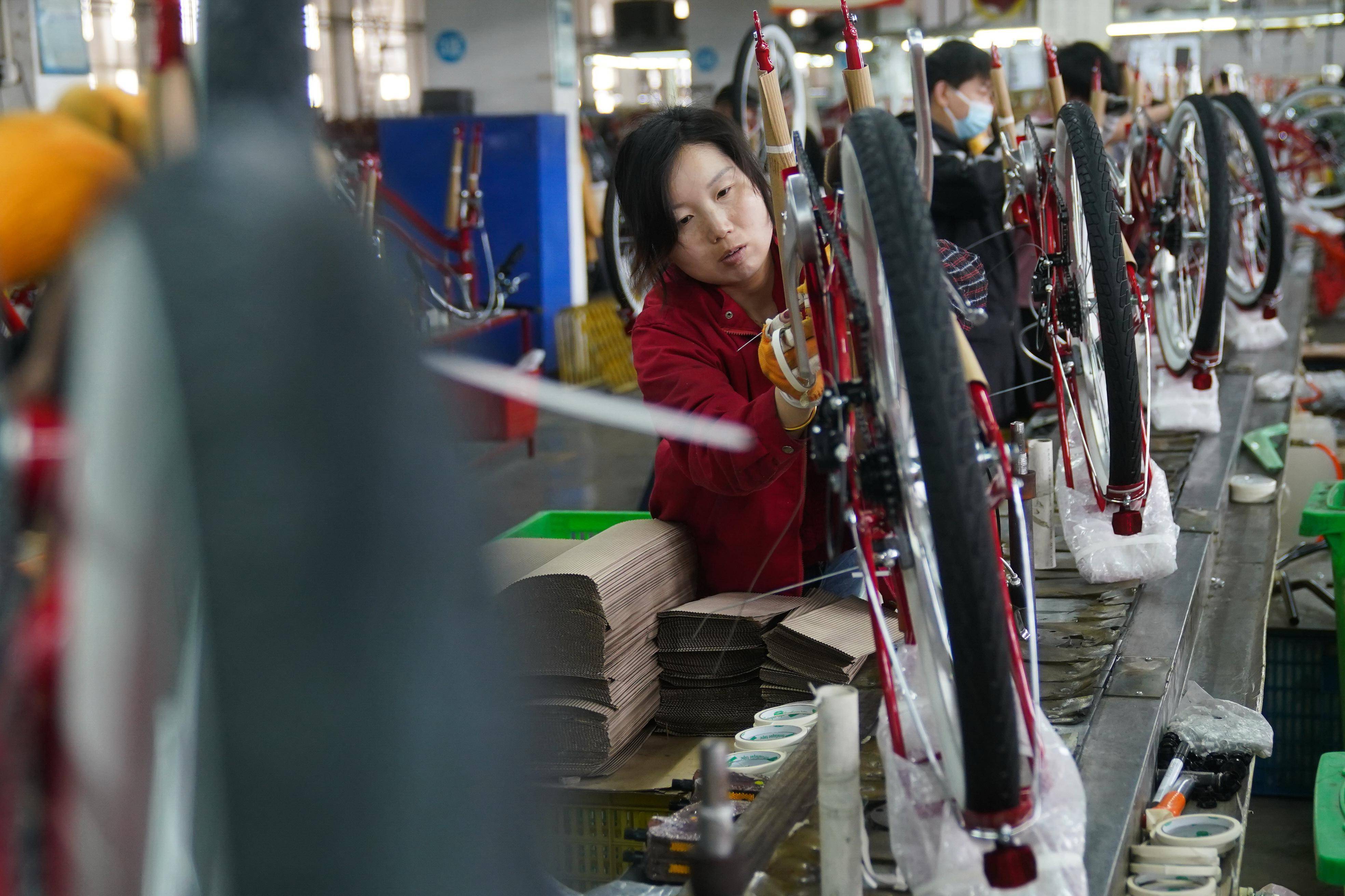 Worker handling road bike components in a factory, representing manufacturers in the list of road bike manufacturers