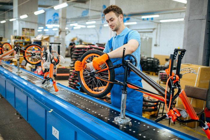 Worker assembling a road bike on a production line, representing capable manufacturers from the list of road bike manufacturers